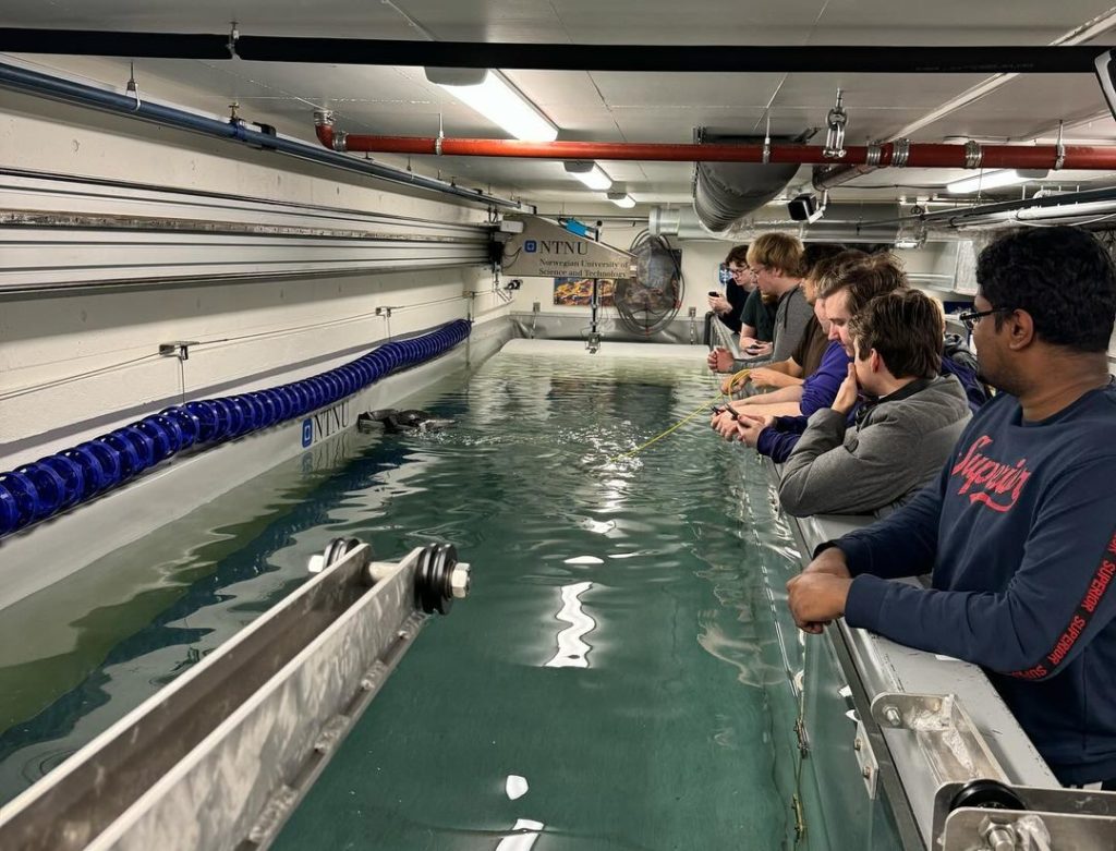 Picture of watertank with people standing around looking at the sub horizon ROV being tested